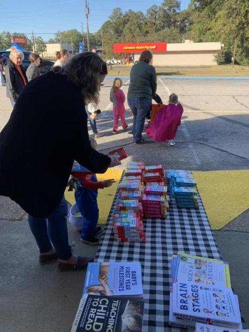 Parent and child picking up books and reading support items at Trunk or Treat Event October 22.jpg